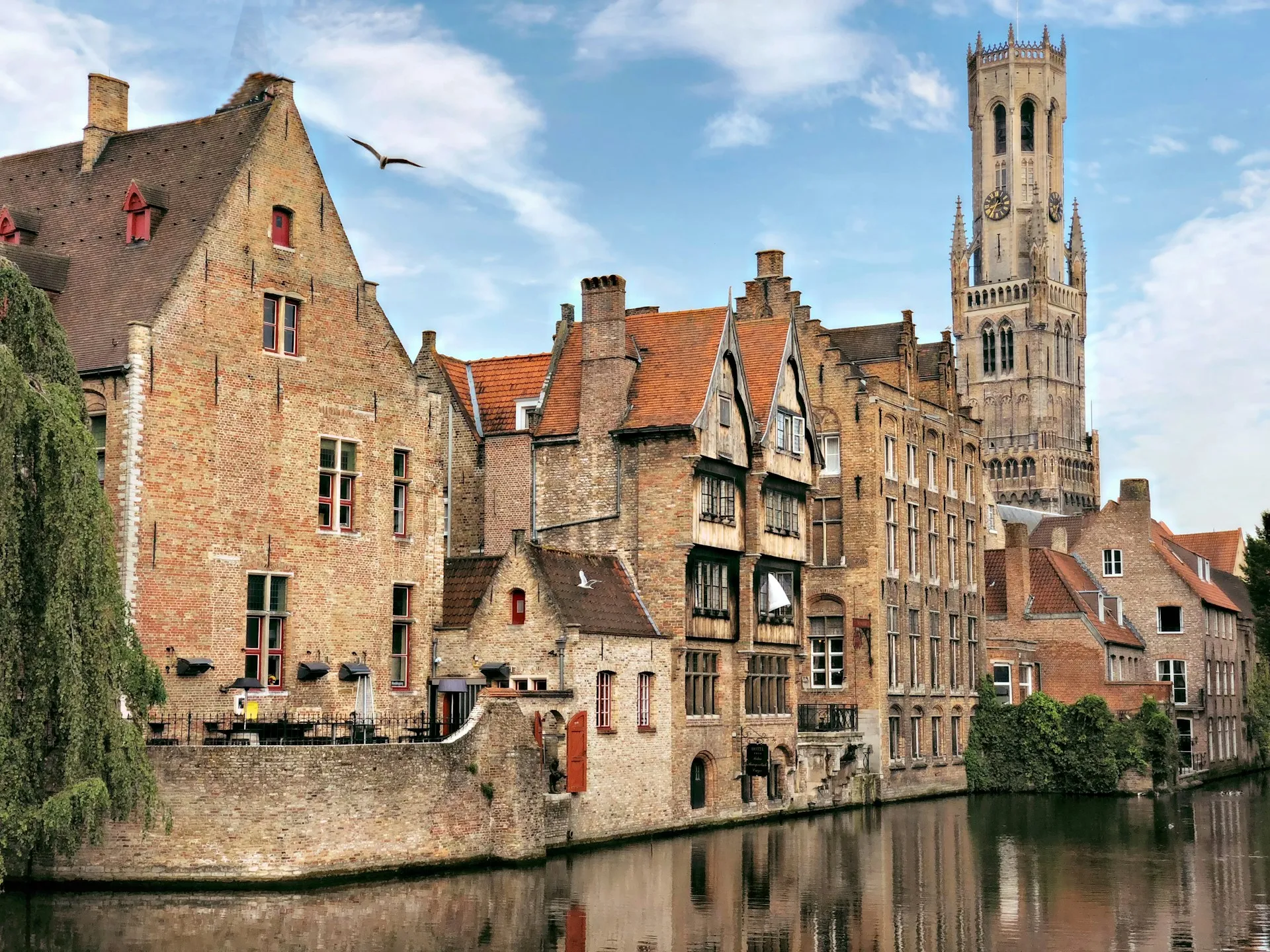 Vue sur les canaux de Bruges avec le Beffroi se dressant au-dessus des toits médiévaux
