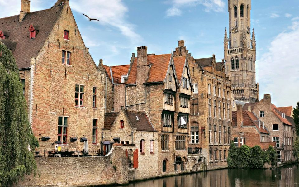 Vue sur les canaux de Bruges avec le Beffroi se dressant au-dessus des toits médiévaux