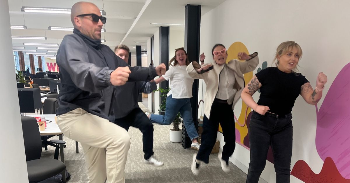 HiBob colleagues jumping and pulling poses in the corridor of their office for a video challenge during their space-themed hybrid team activity