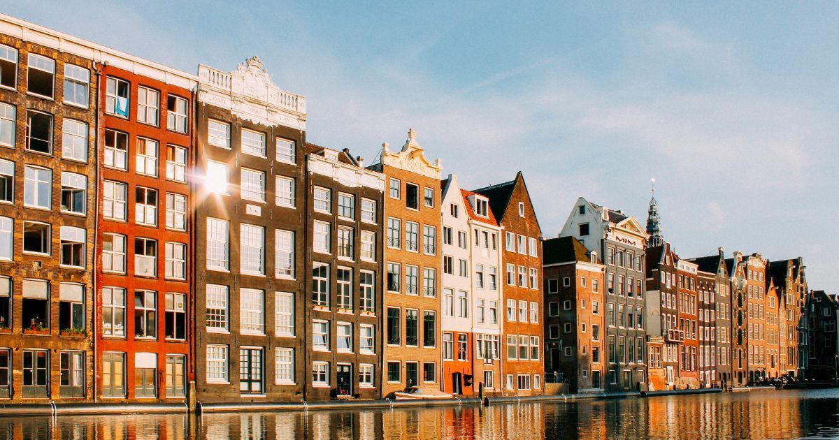 Historische grachtenpanden aan het water in Amsterdam in het avondlicht, in het centrum dat de teams van A&O Shearman verkenden tijdens The Ultimate