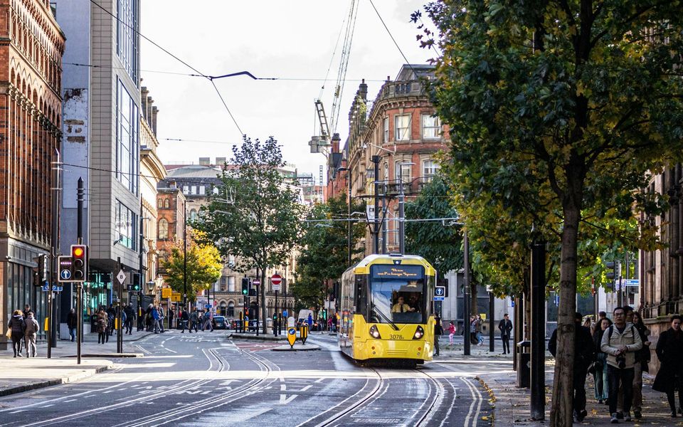 Manchester city street with a yellow tram and pedestrians
