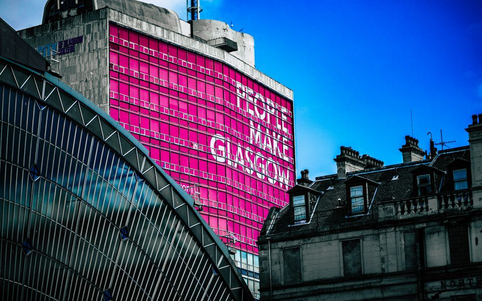 People Make Glasgow sign on a bright pink city building